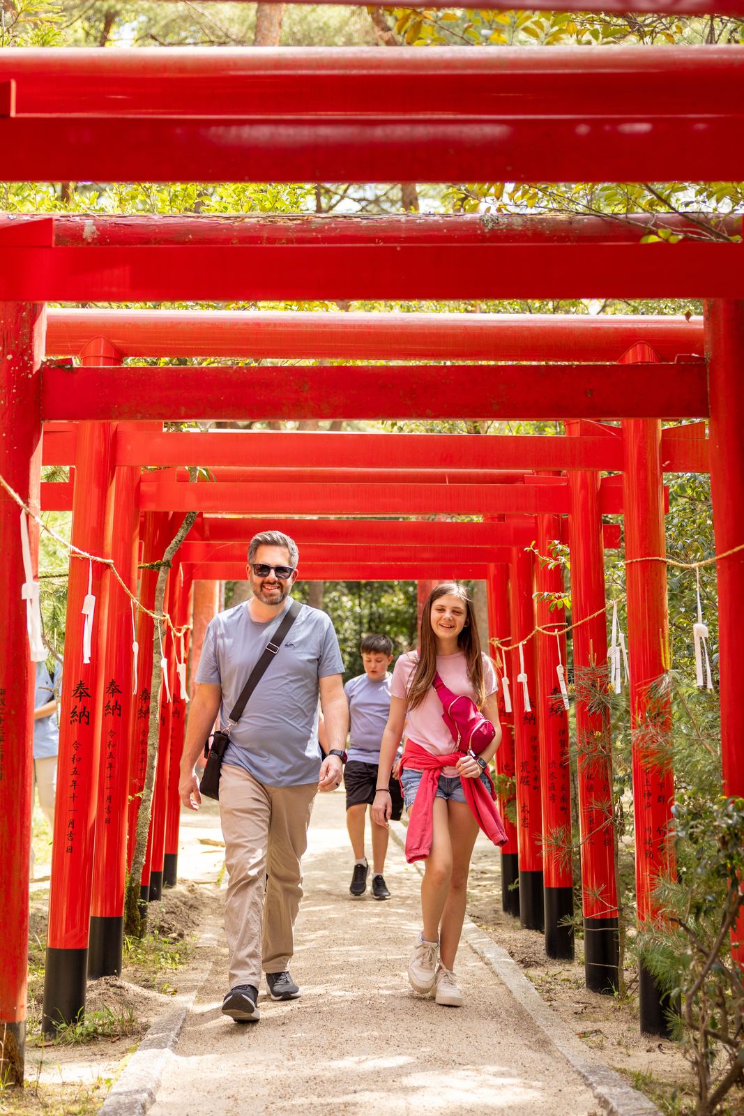Family walking through a tunnel of red torii gates