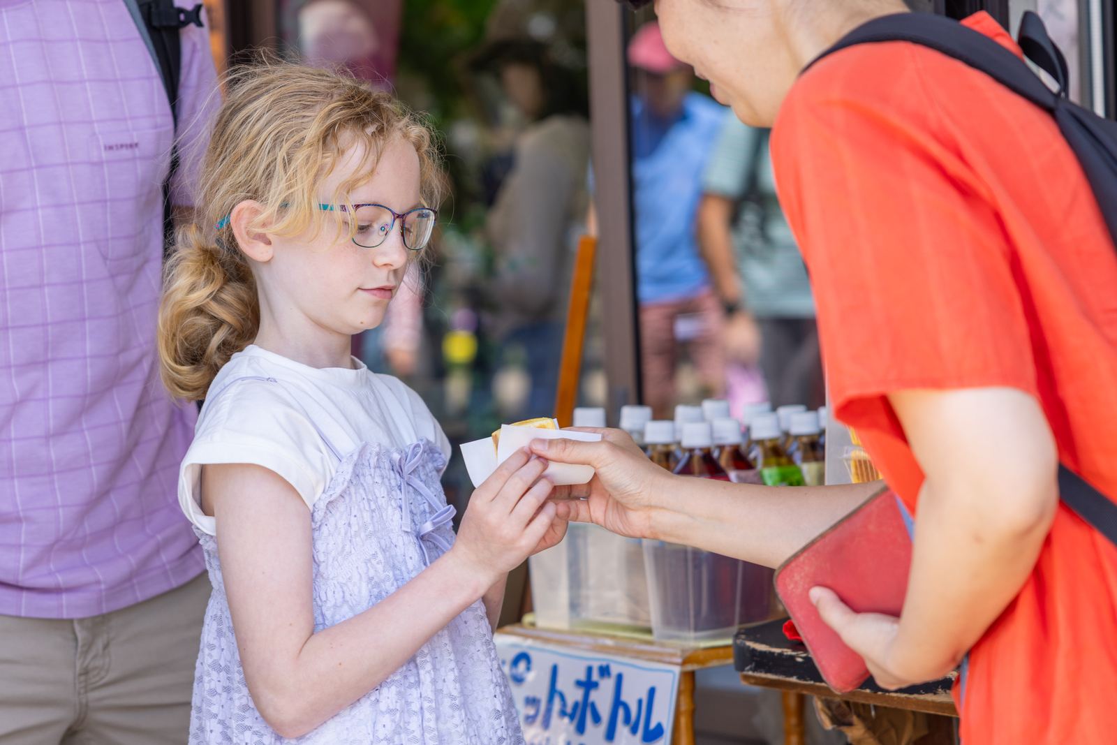 Young guest receiving a street food sample in Takayama