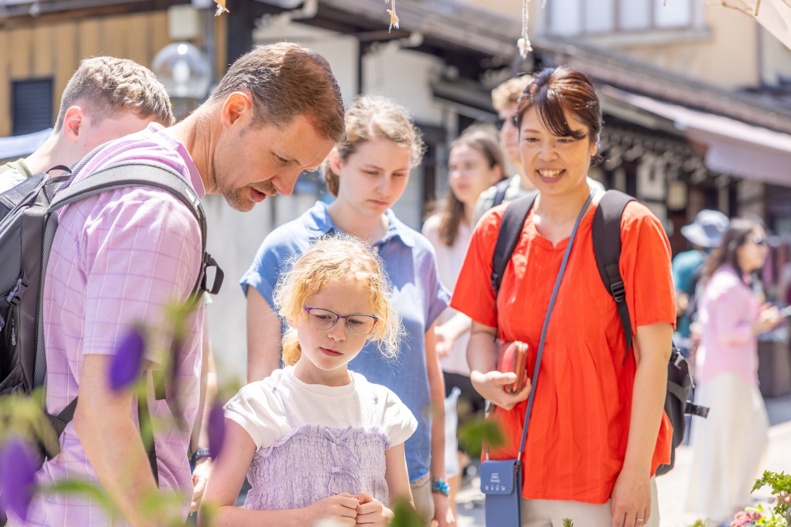 Guide smiling with guests beside Takayama flowers