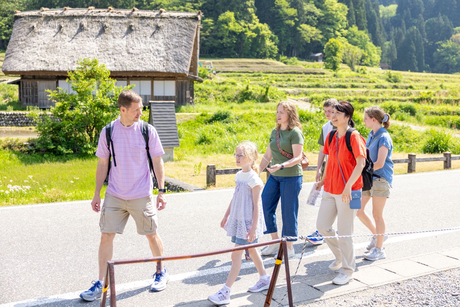 Guests walking with guide past Shirakawa-go rice paddies and thatched farmhouse